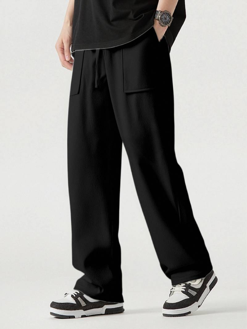 Person wearing black wide-leg pants with a plain background