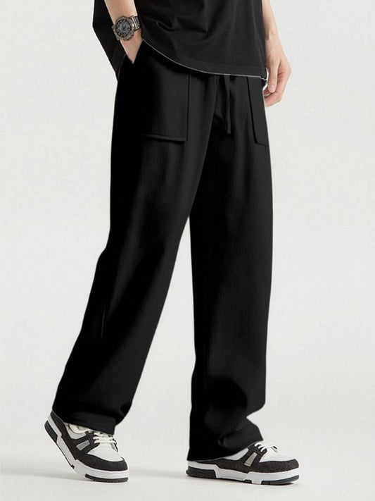 Person wearing black wide-leg pants with a plain background